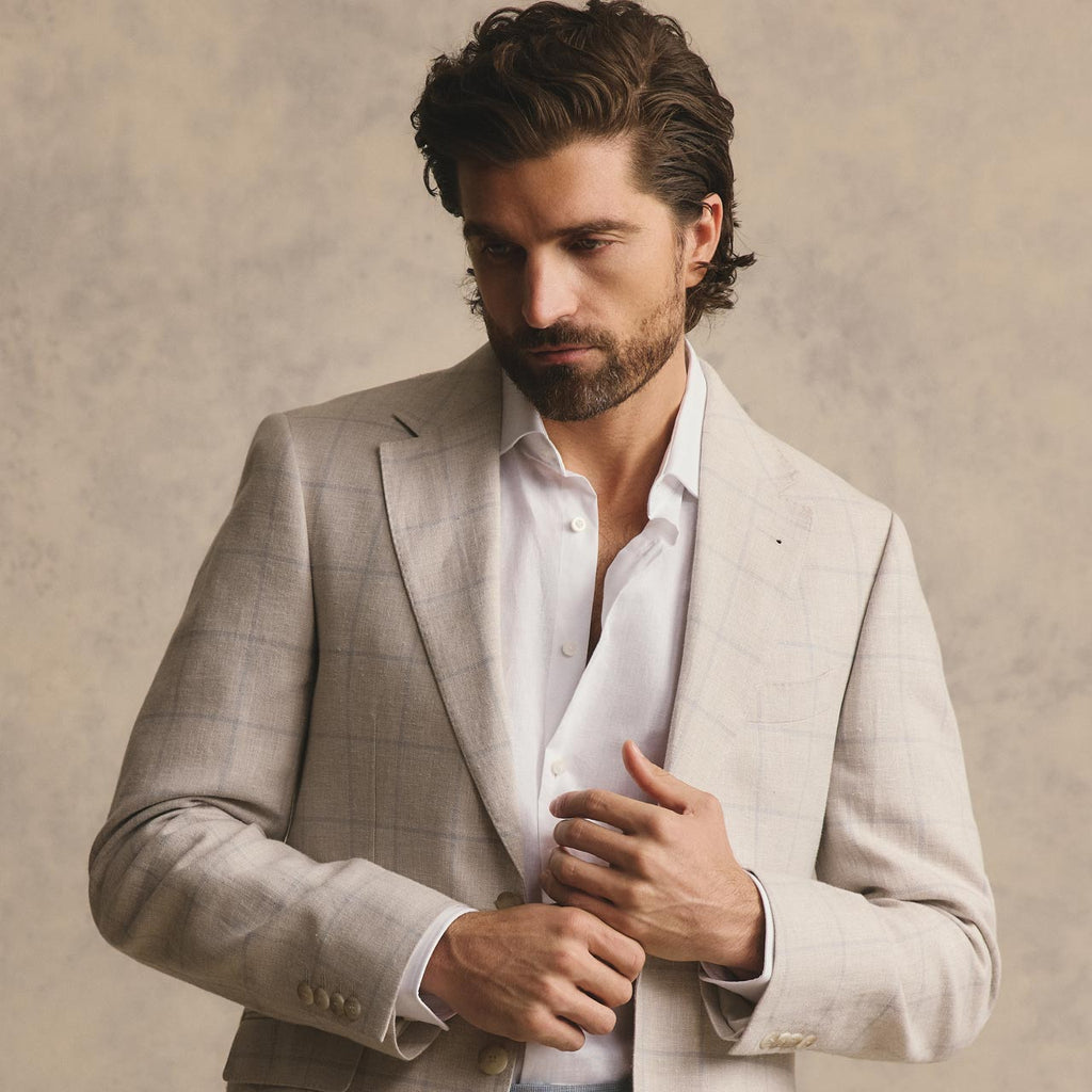 Man wearing a light gray suit with a white shirt against a beige background