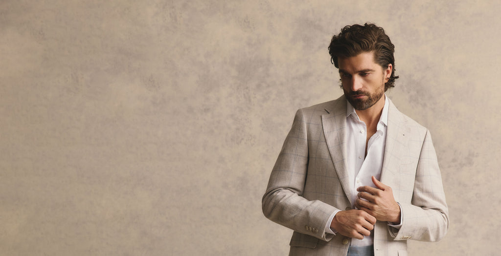 Man adjusting his jacket against a beige background