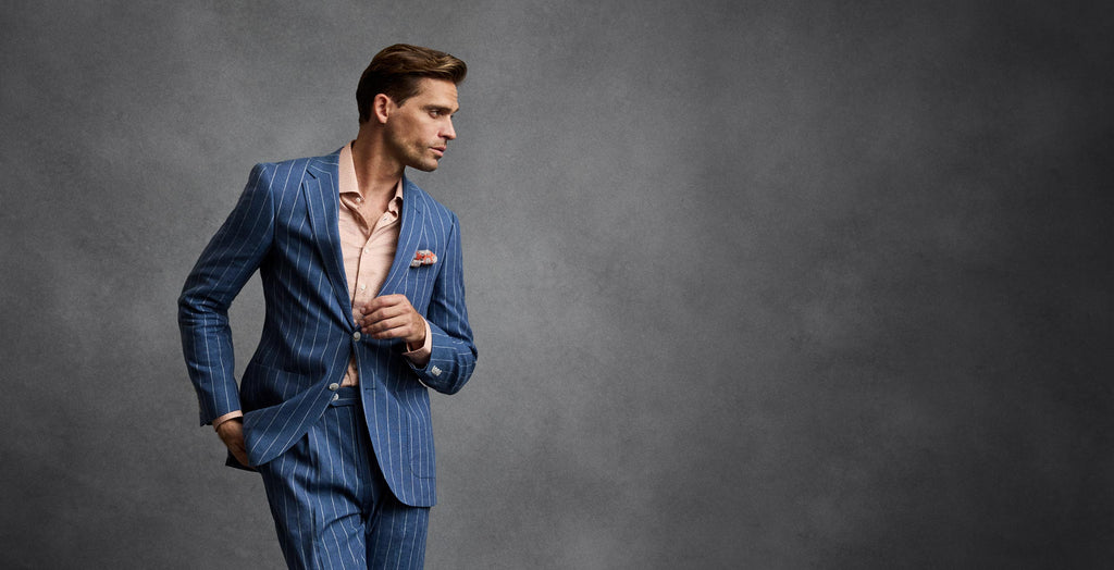 Man wearing a blue pinstripe suit against a gray background