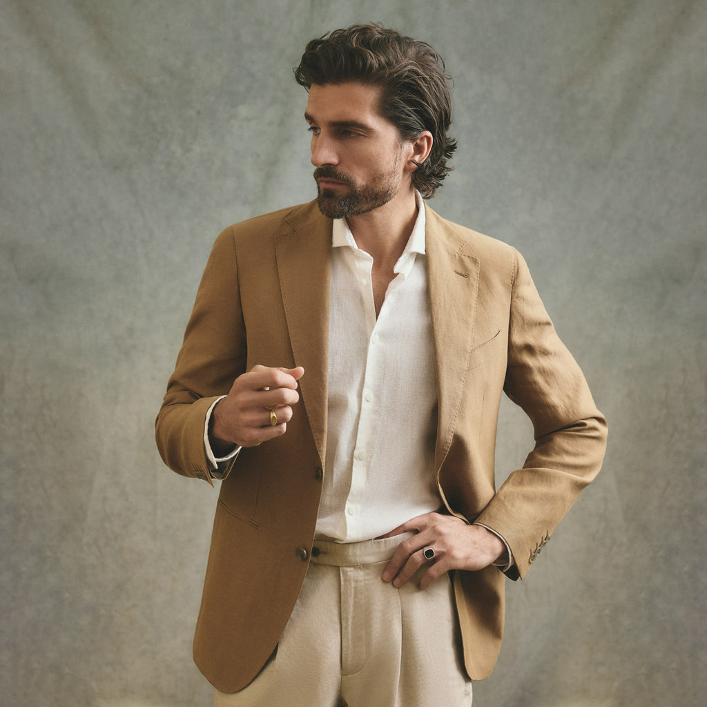 Man wearing a brown suit and white shirt against a neutral background