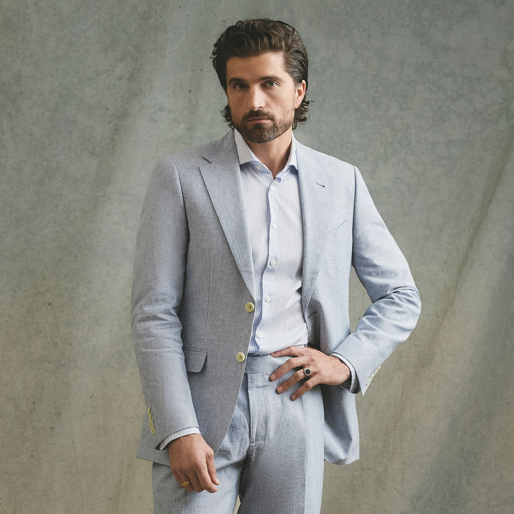 Man wearing a light gray suit against a textured gray background