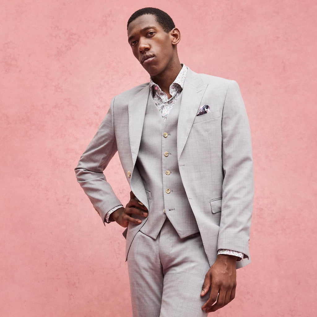 Man wearing a light gray suit with a pink background