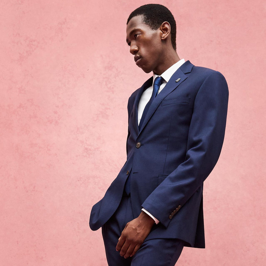 Man wearing a navy suit against a pink background